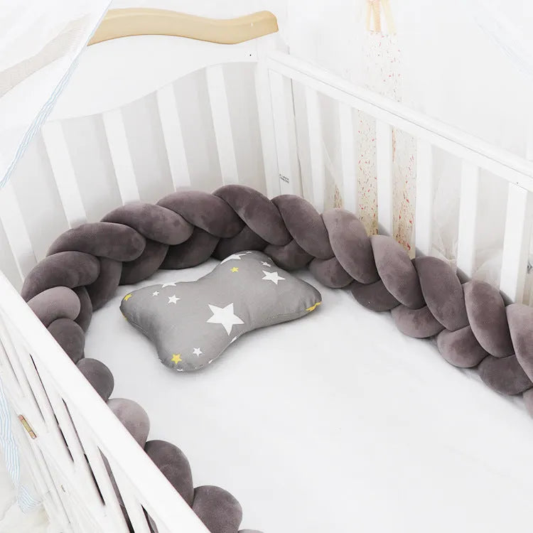 Braided knot baby crib bumper in spandex velvet wrapped around white cot rails.