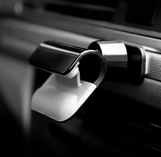 Black universal gravity car phone holder showing 360-degree rotation, mounted on a car air vent.