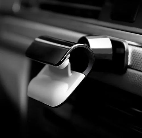 Black universal gravity car phone holder showing 360-degree rotation, mounted on a car air vent.