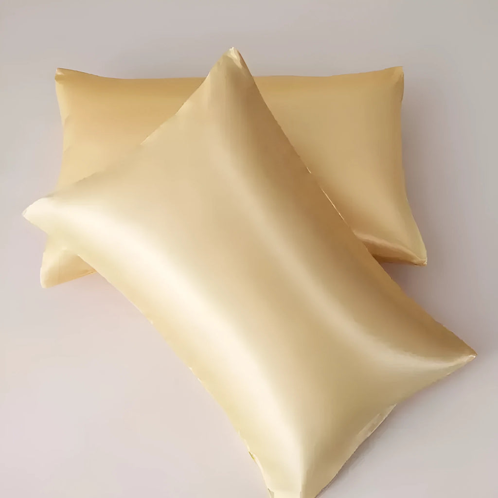 A pair of solid colour satin cloth pillowcases in a chosen shade and size on a bed.