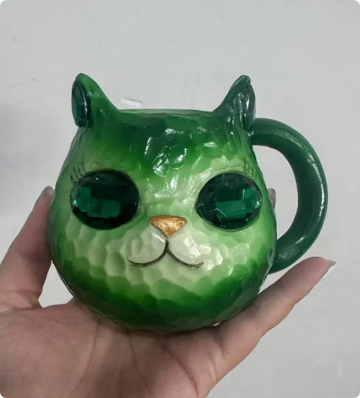 Colourful cat-shaped resin craft ornament in purple, green, blue, or pink on a desk.