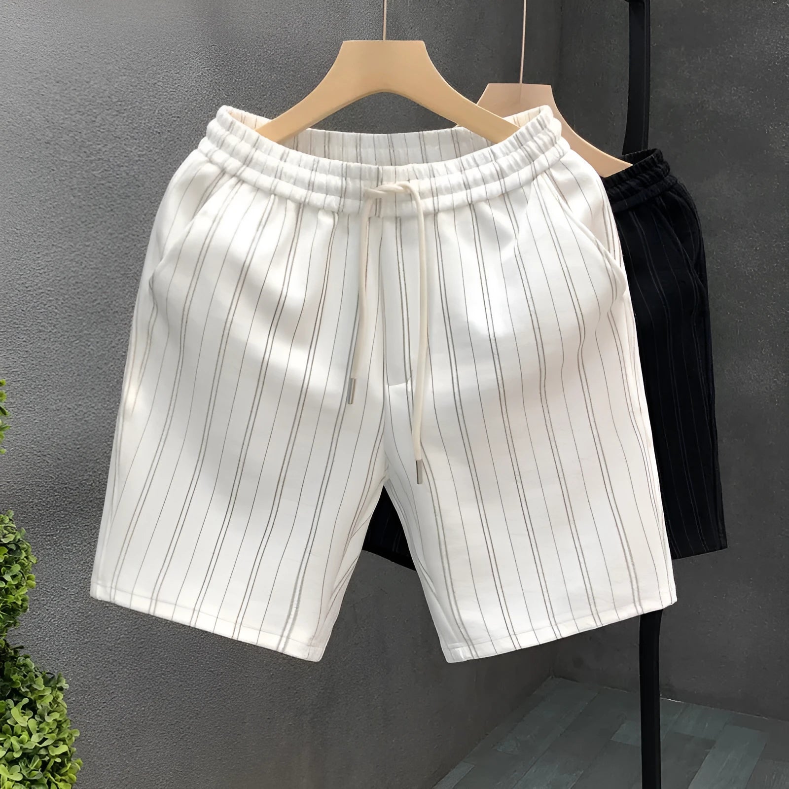 Men's black and white striped fleece-lined casual shorts with an ankle-banded cuff on a hanger.