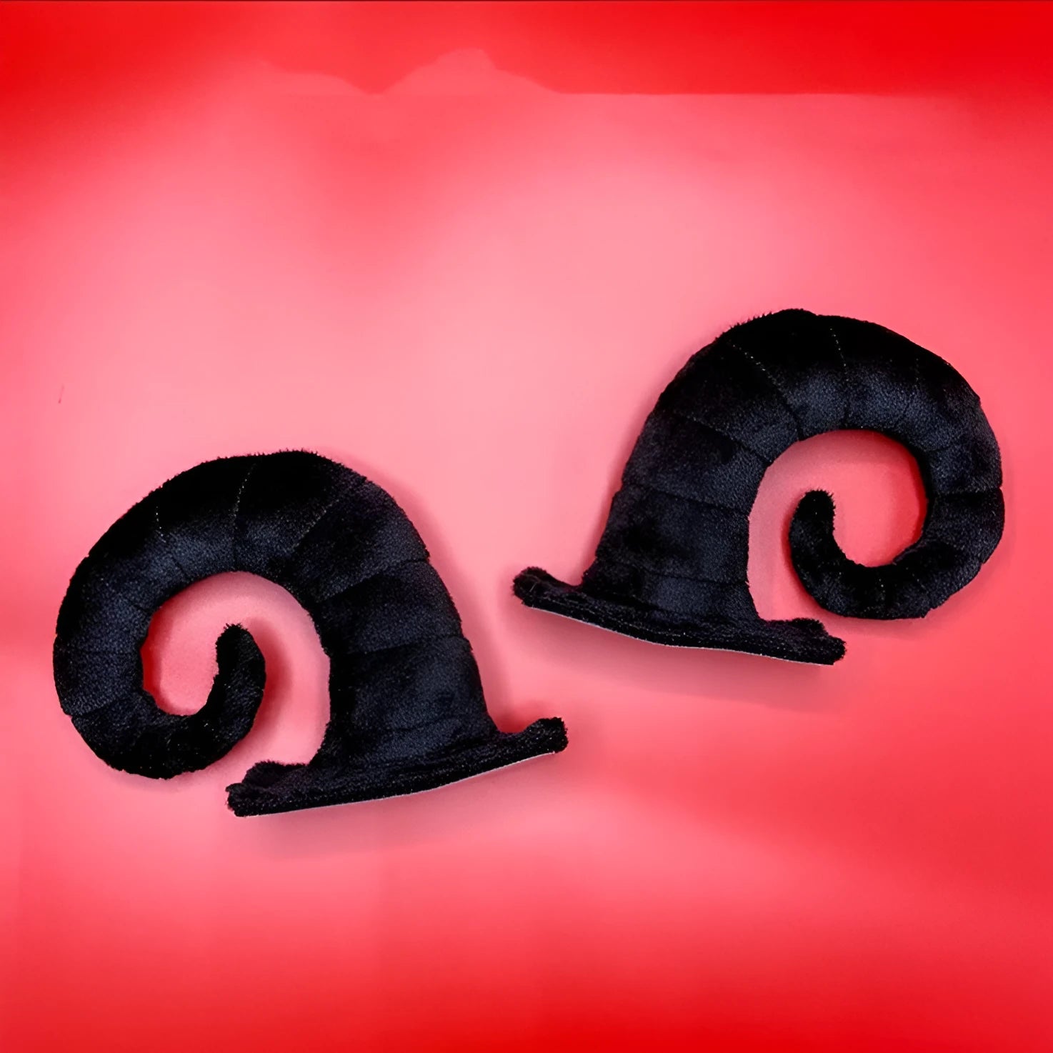 A pair of composite fibre demon bull horn ornaments for motorcycle helmet customisation.