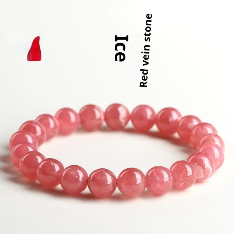 Women's geometric rhodochrosite crystal bracelet with a longevity lock charm on a wrist.