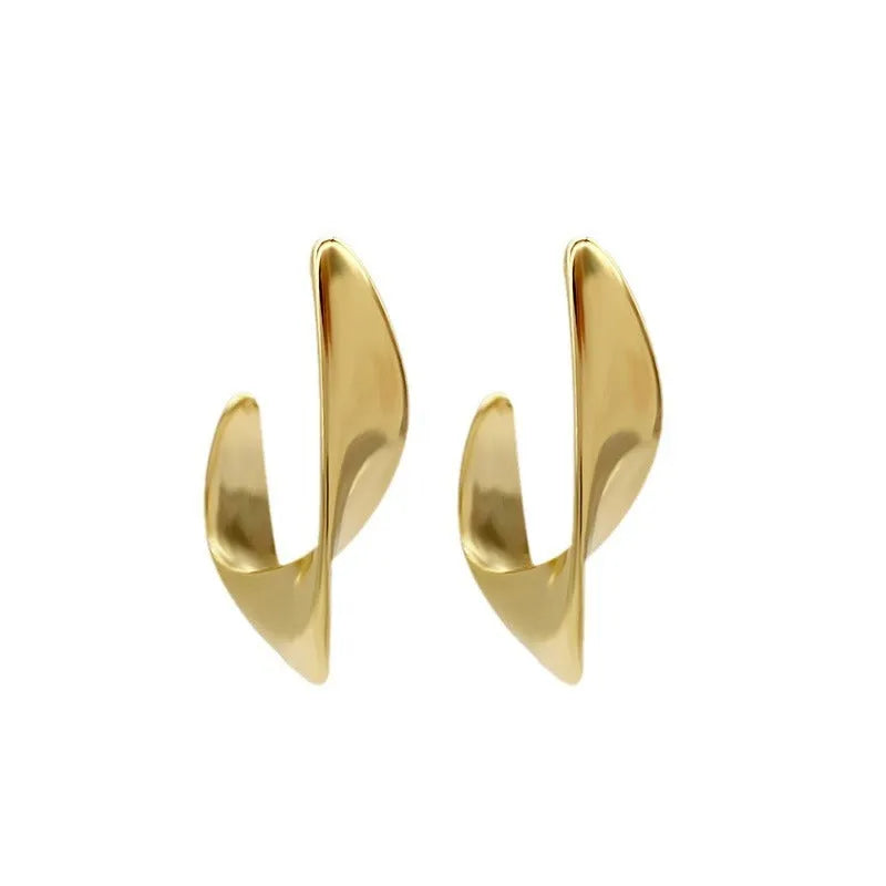 A pair of geometric twisted metal earrings with a round shape in a gold colour.