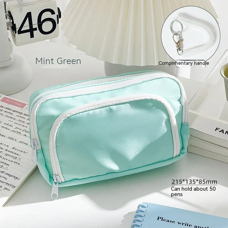 Double-layer pencil case in mint green with gift handle, showing internal divider for stationery organisation