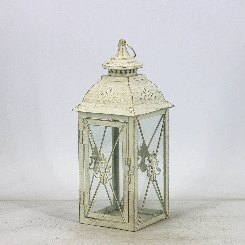 Black wrought iron floor lantern with glass panels on a stone patio.