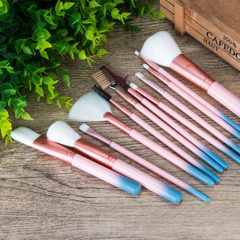 12 pink makeup brushes with synthetic hair bristles and plastic handles on a light surface