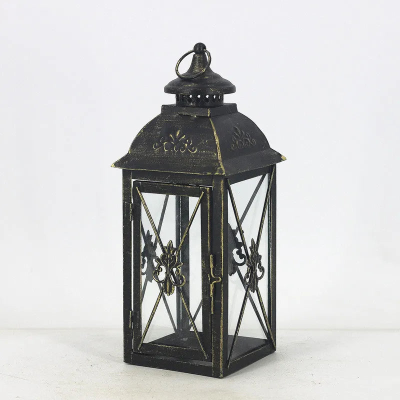 Black wrought iron floor lantern with glass panels on a stone patio.