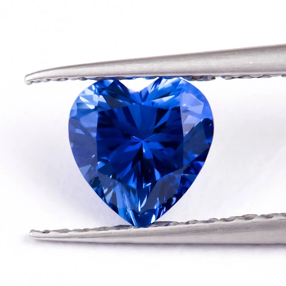 Royal blue loose gemstone in heart, round, and pear shapes on a white background.