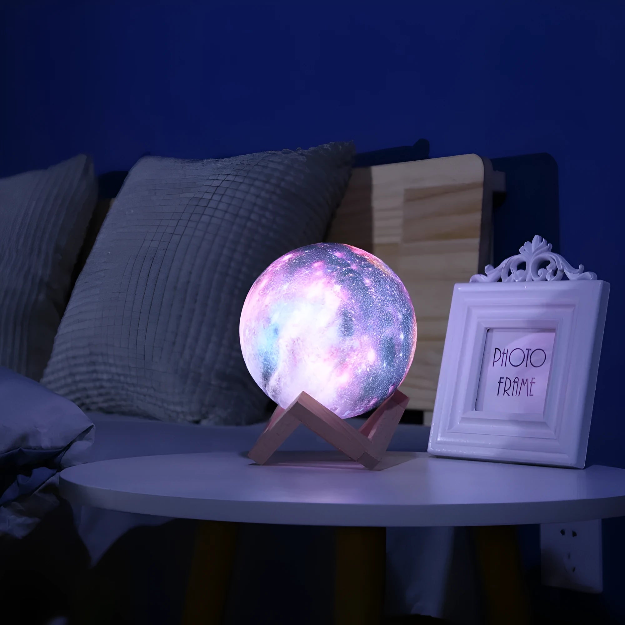 3D printed white lunar lamp sphere glowing on a surface, showing crater texture with a remote control nearby.
