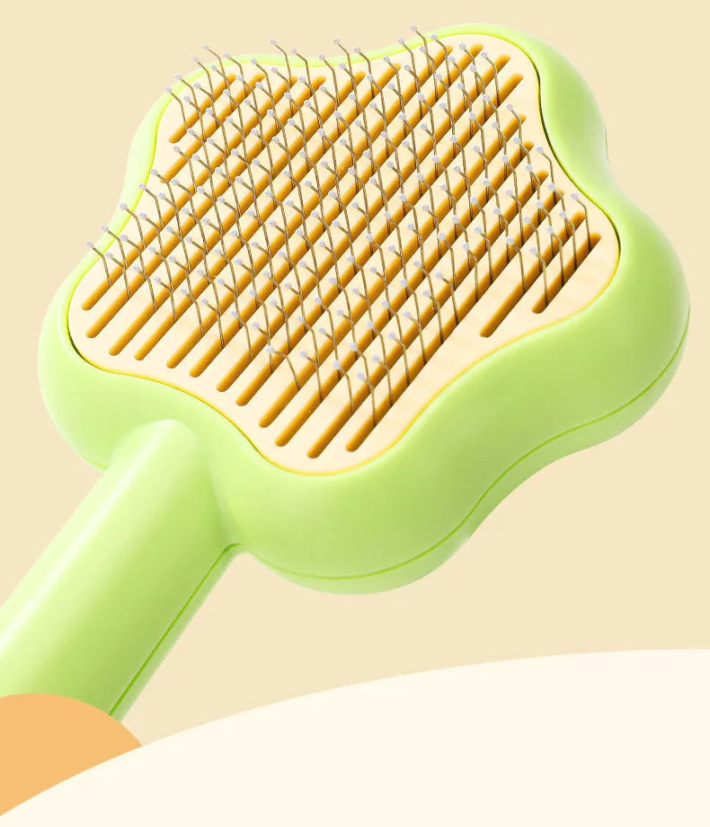 Green and yellow self-cleaning cat grooming comb with stainless steel needles on a white background.