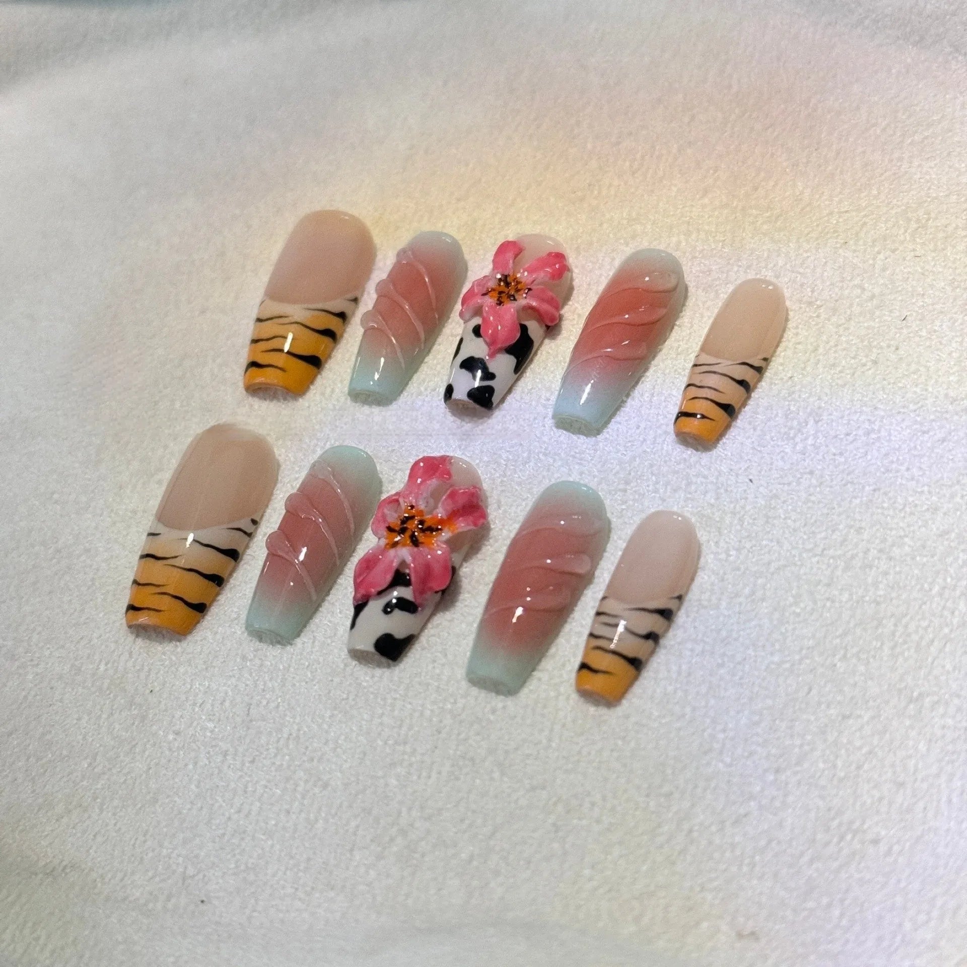 Close-up of hand-carved acrylic press-on nails with a Lily zebra pattern, floral, and leopard print design.