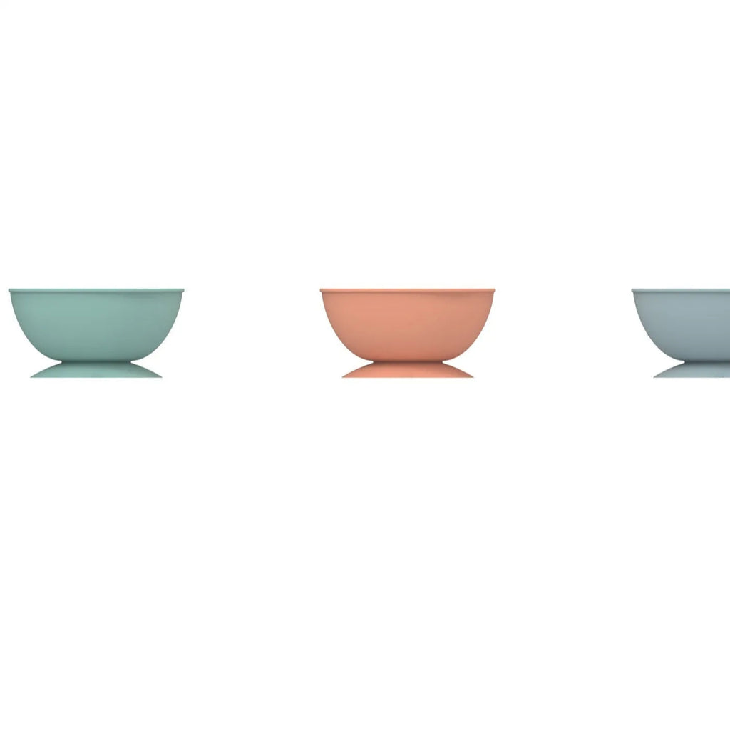 Cyan silicone dog bowl with slow feeder ridges and suction cup base on a table.