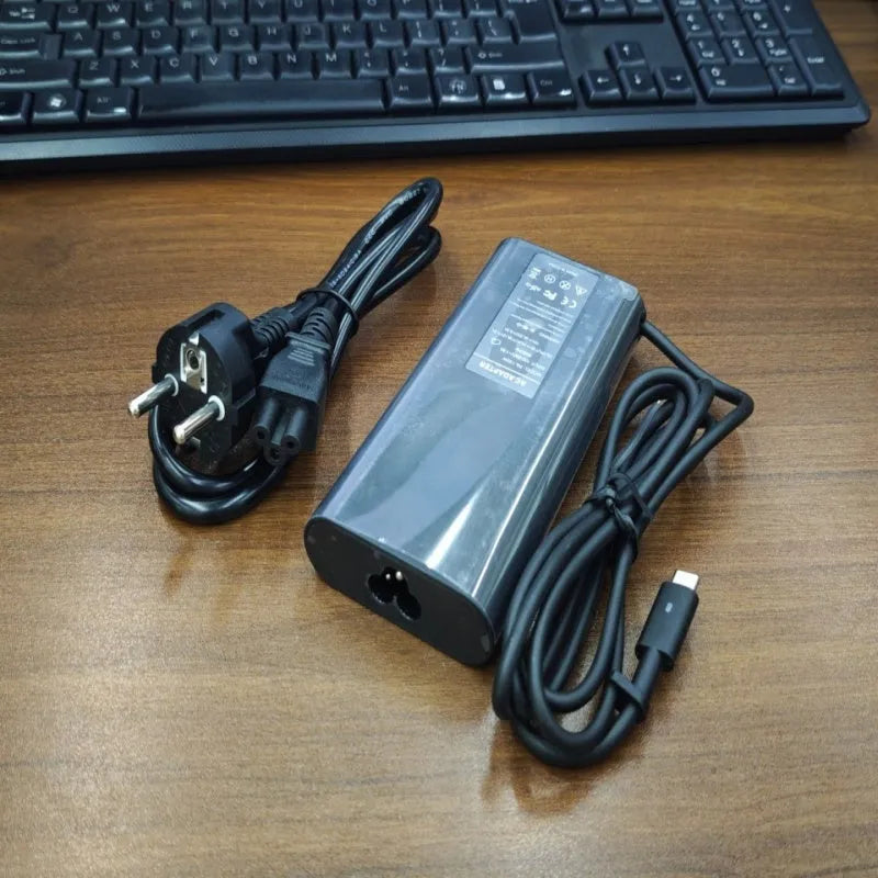 Black 65W USB-C laptop power adapter with a set of international plug cords for UK, US, EU, AU and SA sockets.