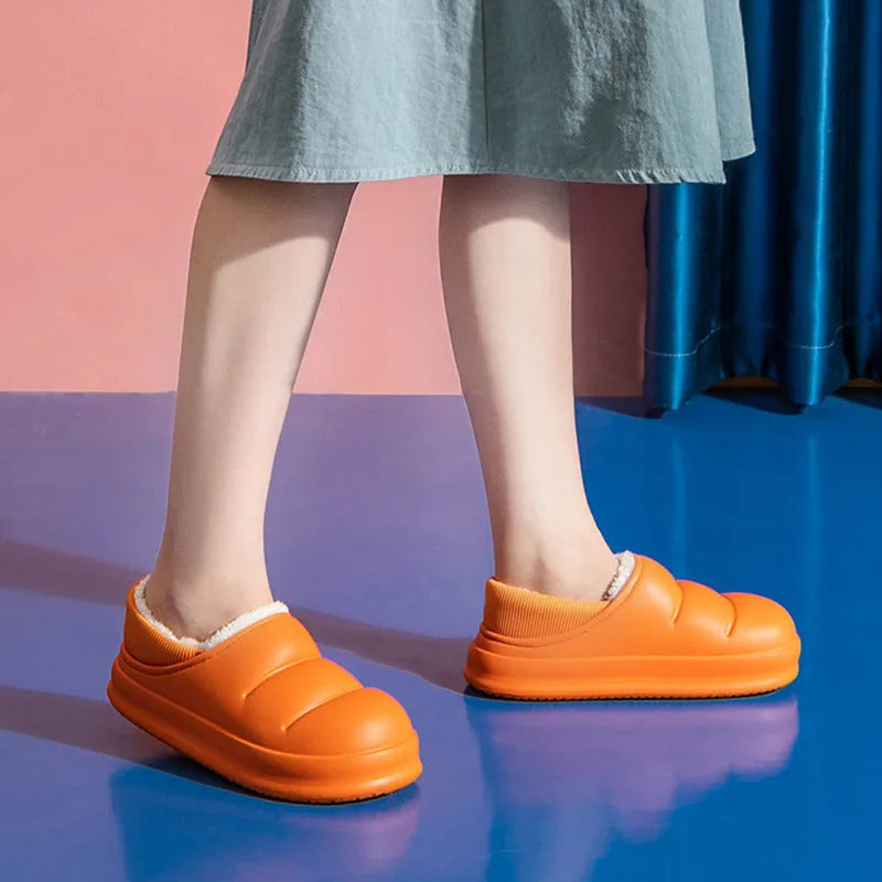 Green waterproof EVA garden slippers with plush lining and a non-slip sole, shown on a wooden deck.