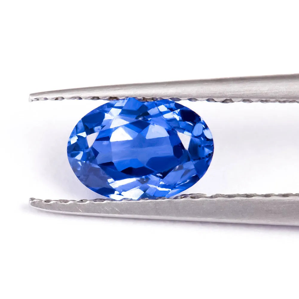 Royal blue loose gemstone in heart, round, and pear shapes on a white background.