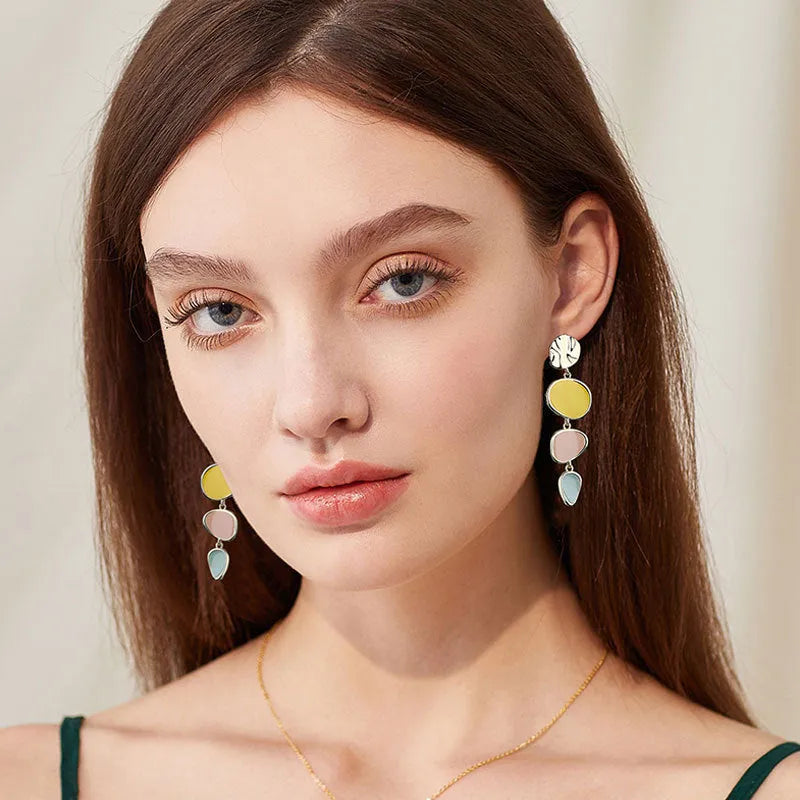 A pair of simple disc-shaped alloy earrings with a blended Morandi three-colour oil drip finish.