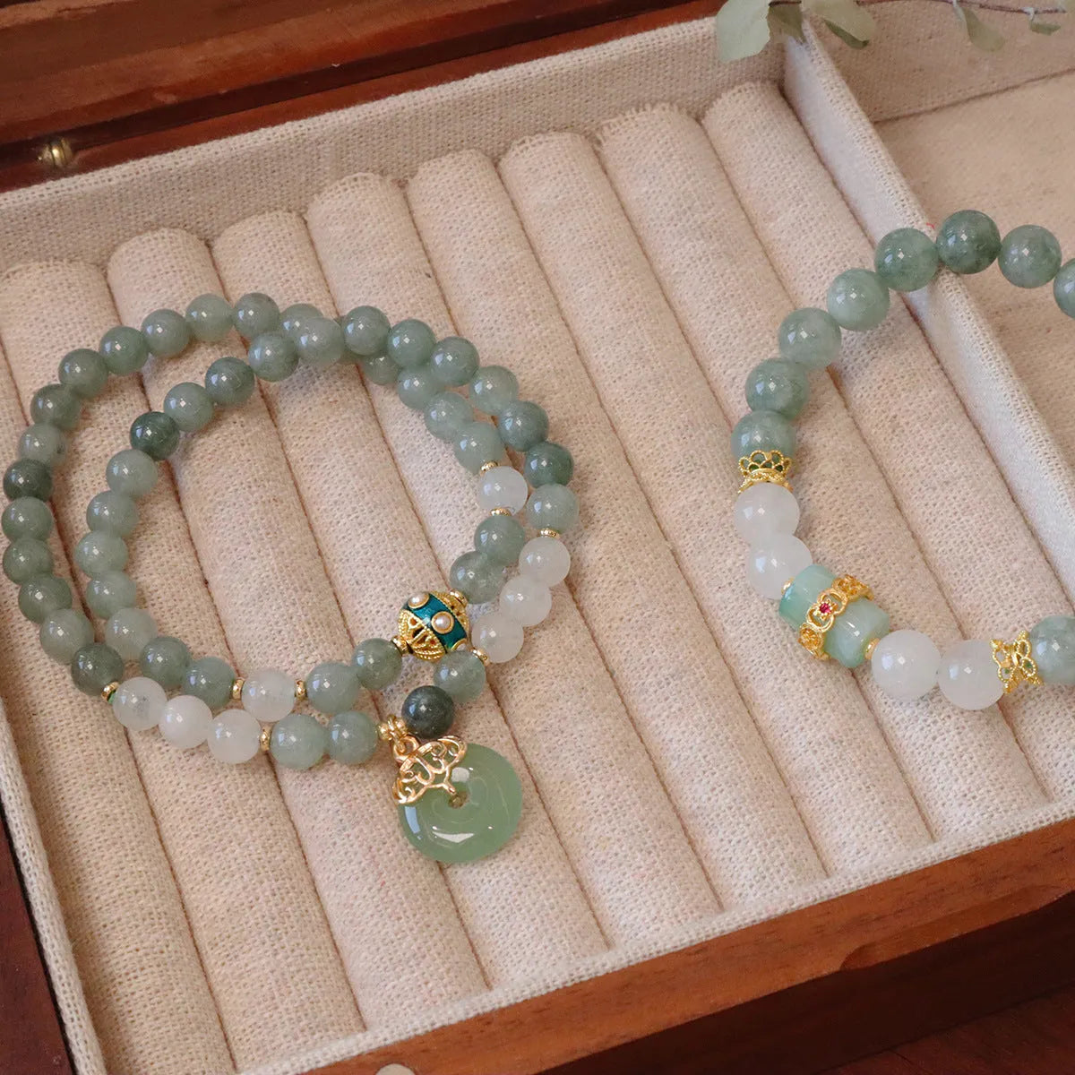 Close-up of a women's Myanmar jade bracelet with a geometric metal safety buckle pendant and lucky beads.
