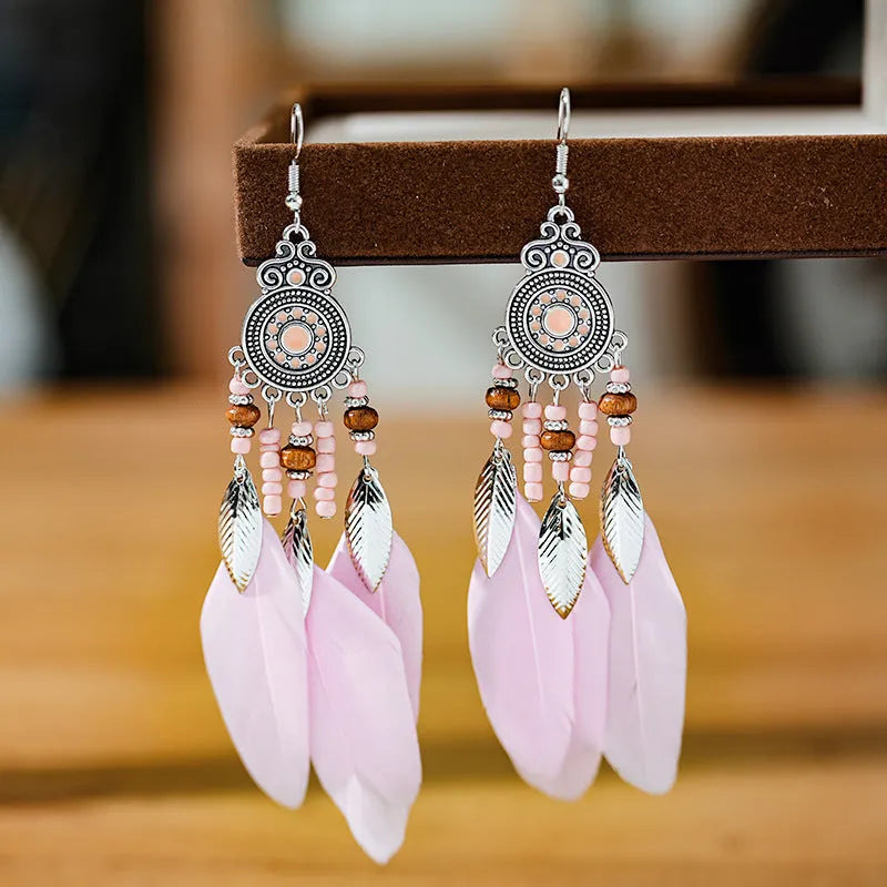 Close-up of a pair of bohemian-style feather and leaf design drop earrings in alloy, showing the electroplated finish.