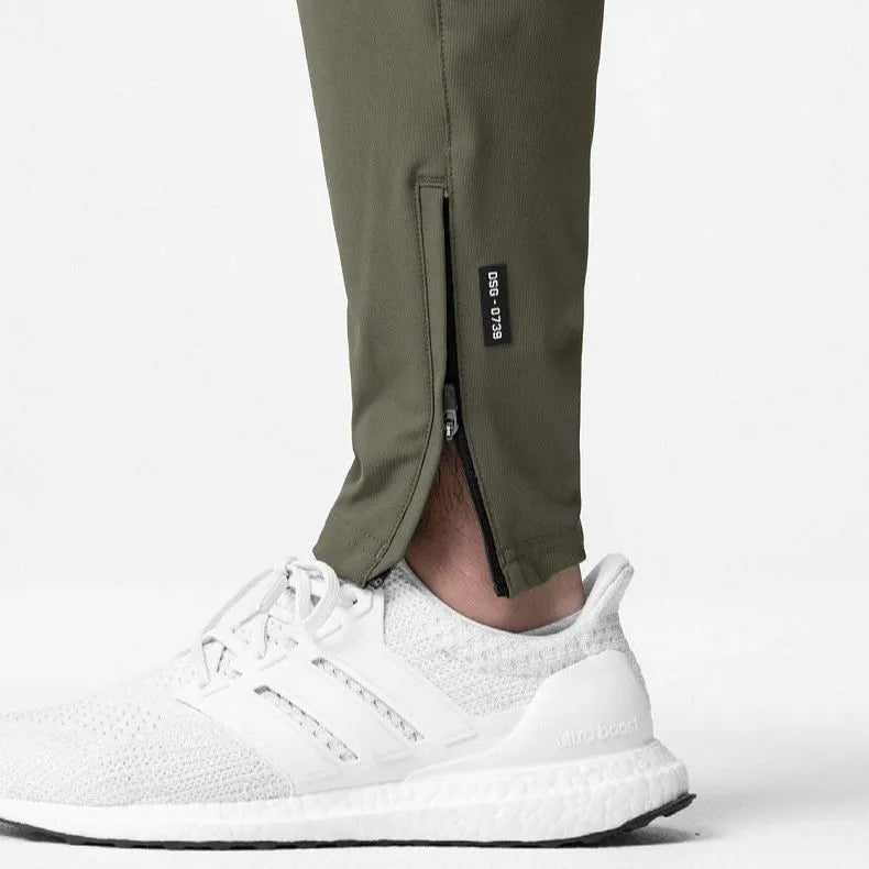 Men's grey loose-fit running pants with ankle ties on a gym floor