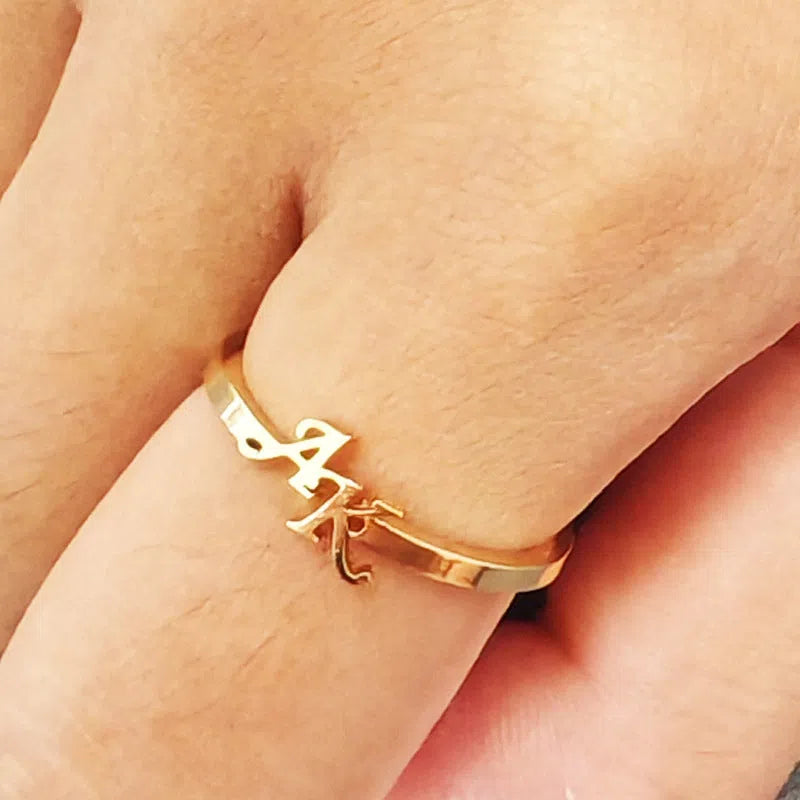 Customised two-letter open ring in stainless steel silver and gold electroplated finish on a white background