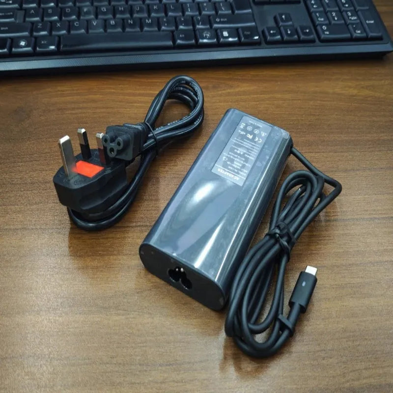 Black 65W USB-C laptop power adapter with a set of international plug cords for UK, US, EU, AU and SA sockets.