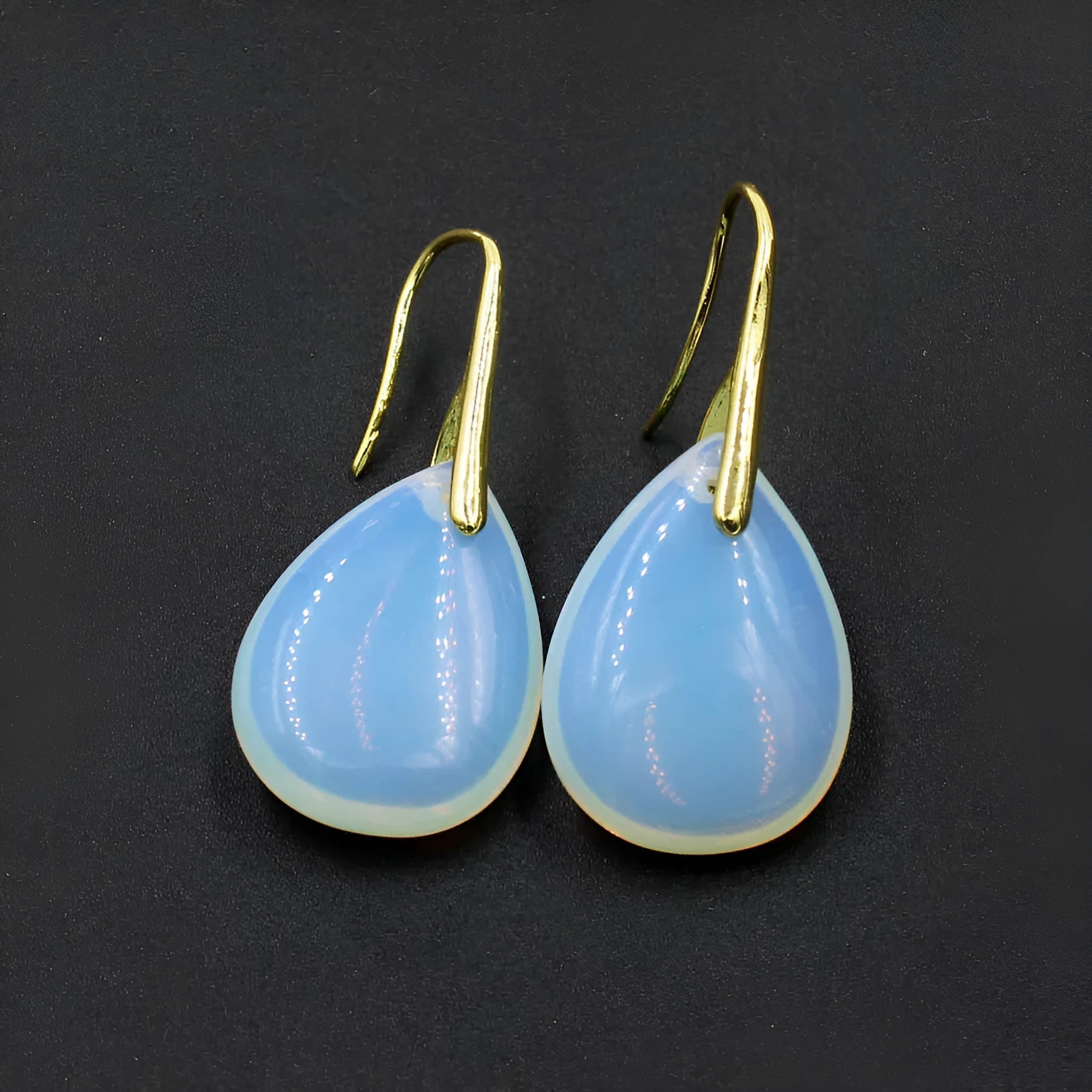 A pair of geometric water drop earrings made from crystal, shown in one of nine available colours like amethyst or obsidian.