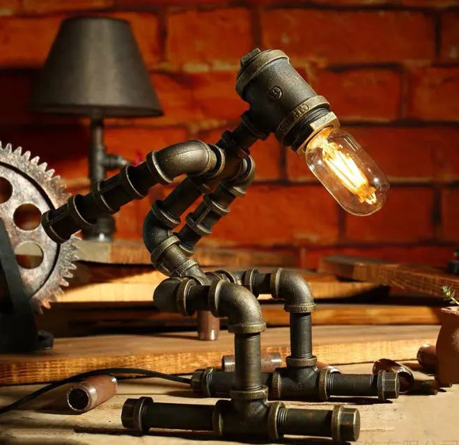 Green bronze vintage industrial iron pipe desk lamp on a wooden table.