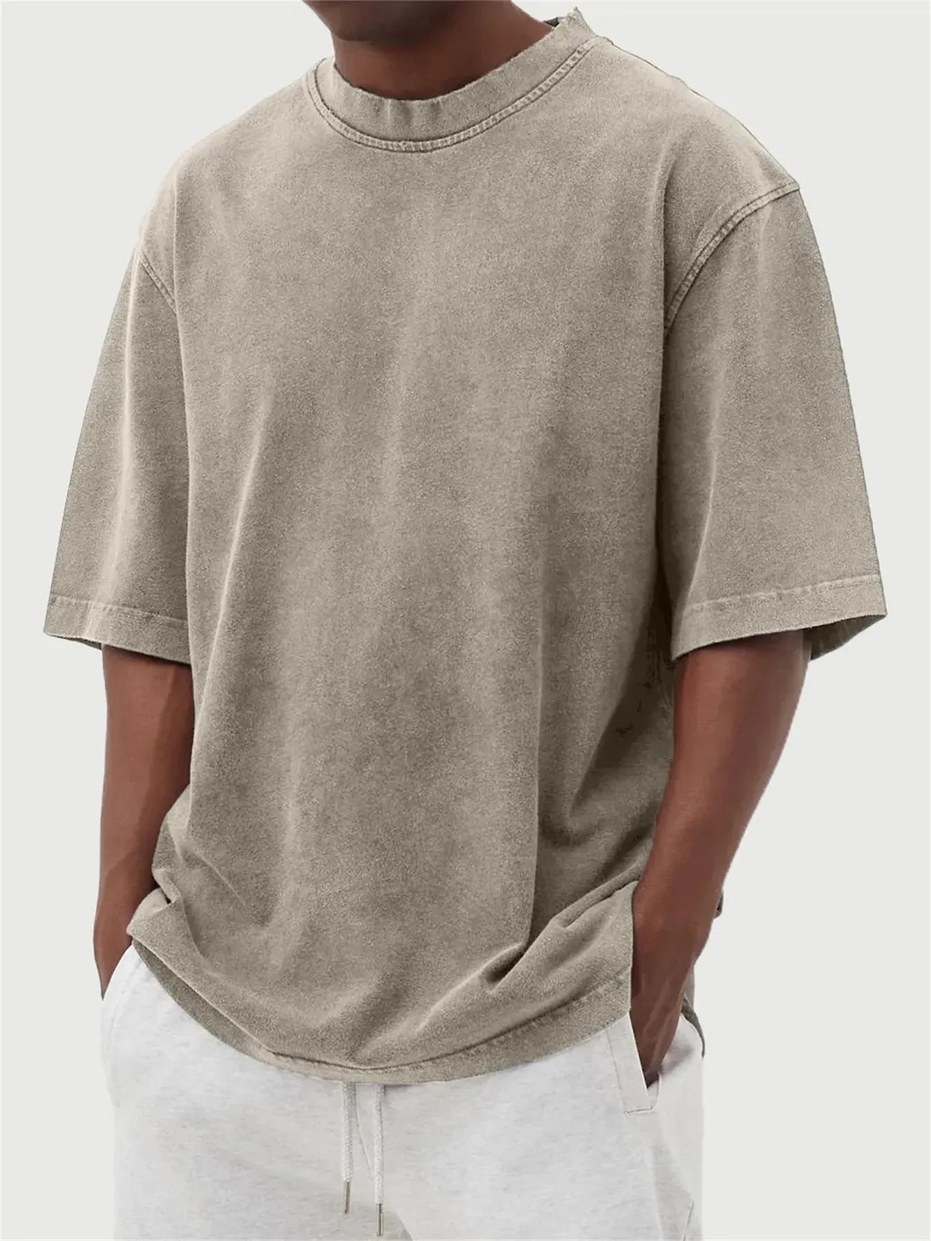Man wearing a loose-fit, stone-washed grey t-shirt with a distressed solid colour finish and half sleeves.