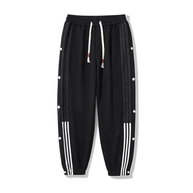Men's black high-waist sweatpants with ankle-tied cuffs and a drawstring waist on a grey background.