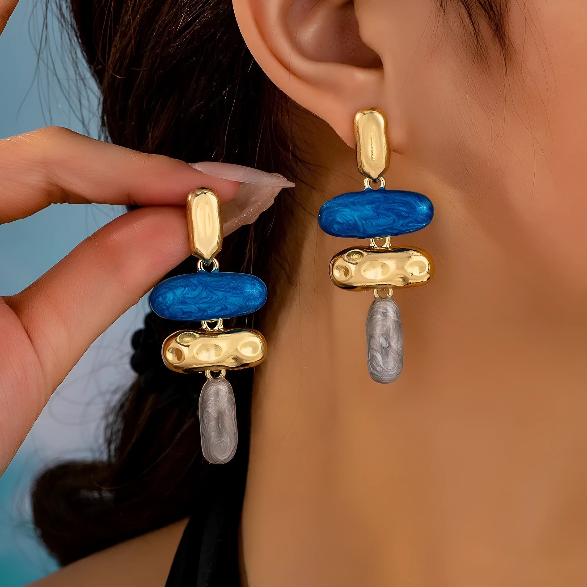 A pair of simple geometric stud earrings with a multicolour electroplated finish on a white background.