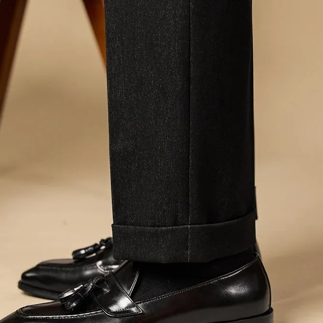 Men's black polished leather tassel loafers with a rubber sole on a white background.