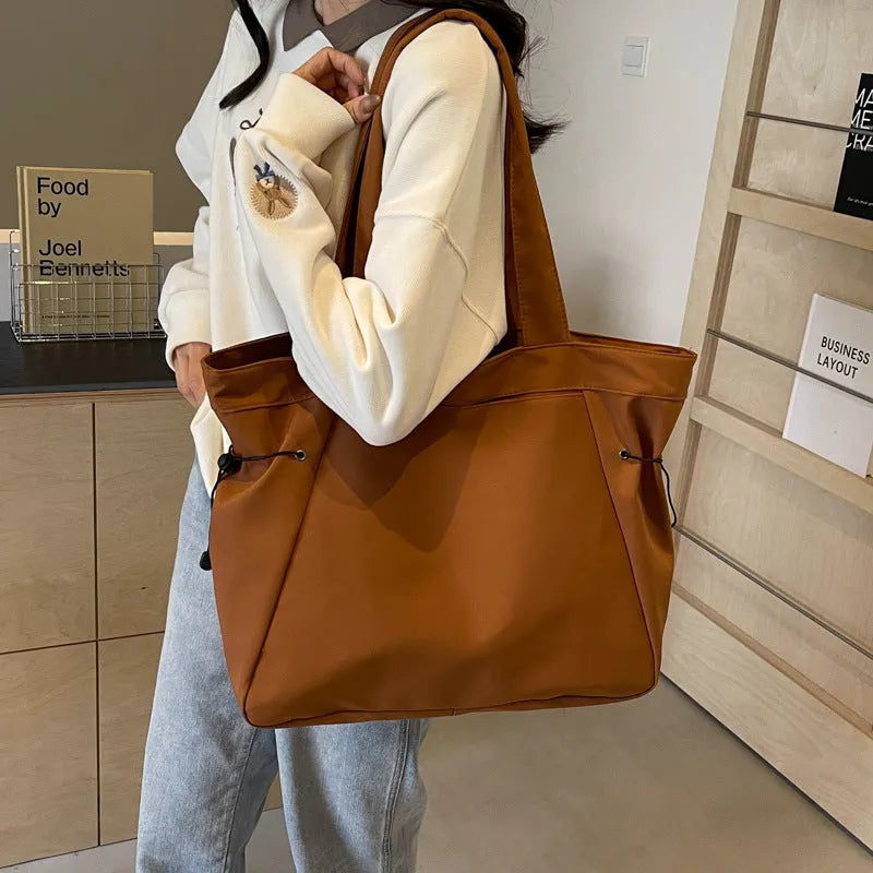 Soft folding shoulder tote bag in Oxford cloth shown in one of five colour options: black, brown, dark grey, light grey, or purple.