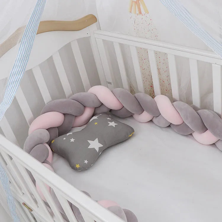 Braided knot baby crib bumper in spandex velvet wrapped around white cot rails.