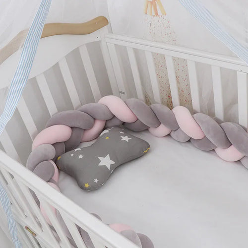 Braided knot baby crib bumper in spandex velvet wrapped around white cot rails.