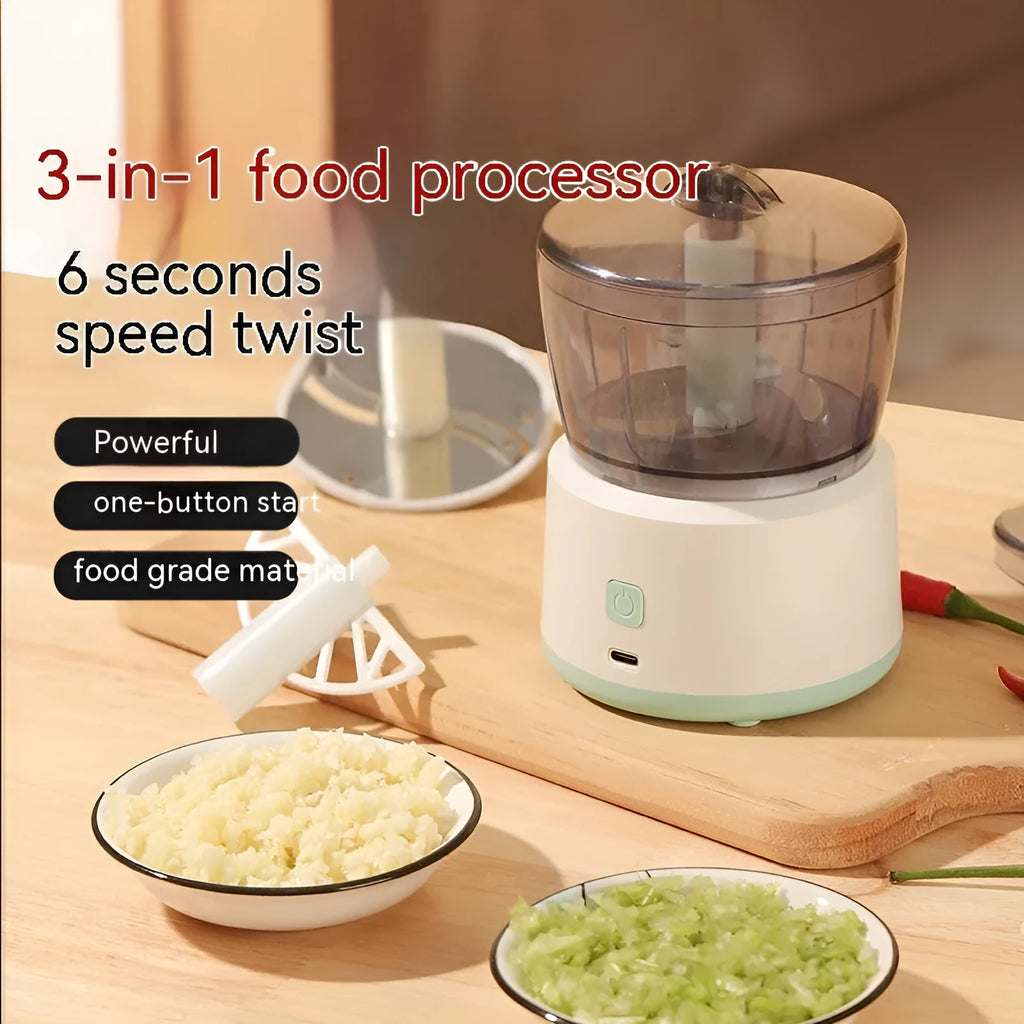 Mini electric food processor in light green with transparent cup and stainless steel blades on countertop.
