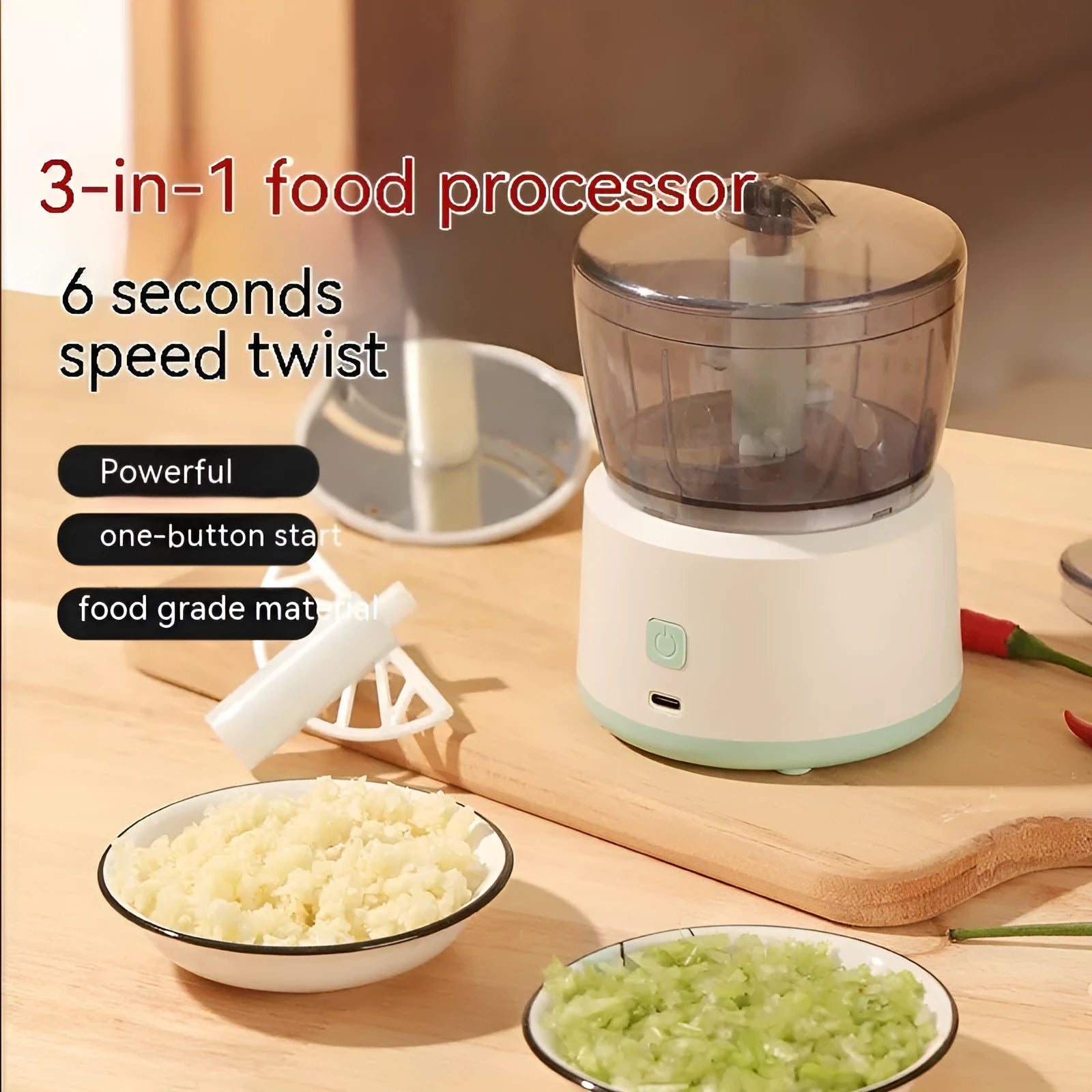 Mini electric food processor in light green with transparent cup and stainless steel blades on countertop.
