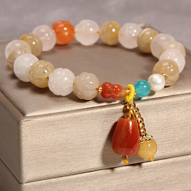Yellow agate crystal bracelet with gold silk adjustable cord on a wrist, showing khaki coloured beads.
