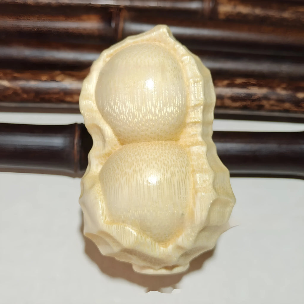 Solid natural bamboo ornament carved into a peanut shape on a plain background.