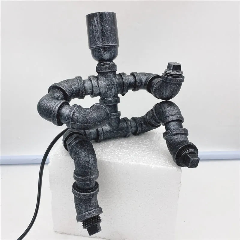 Industrial vintage table lamp shaped like a robot made from iron water pipes in a retro colour.