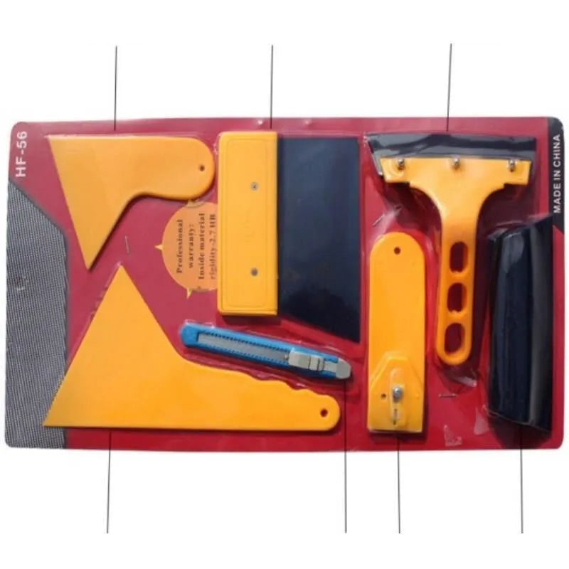Seven-piece automotive film tool set with scrapers, knives, and a pressing block on a work surface.