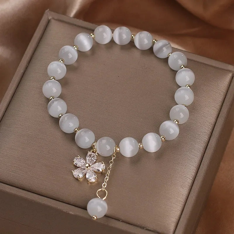 White cat's eye crystal bracelet for women with a small flower tassel and a morganite-coloured safety buckle.