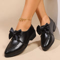 Women's British-style leather-look shoes with decorative bow detail on pointed toe