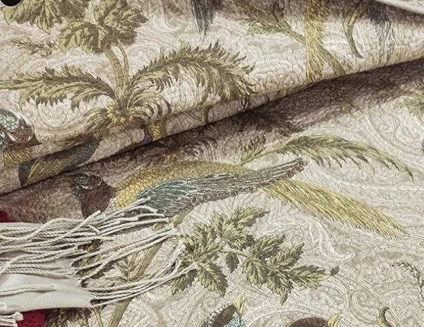 Blue cotton quilted bedspread with detailed floral and bird pattern, shown on a bed.