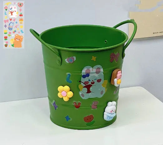 Round metal pen holder in a choice of colours including pink, green, red, white and yellow on a desk.