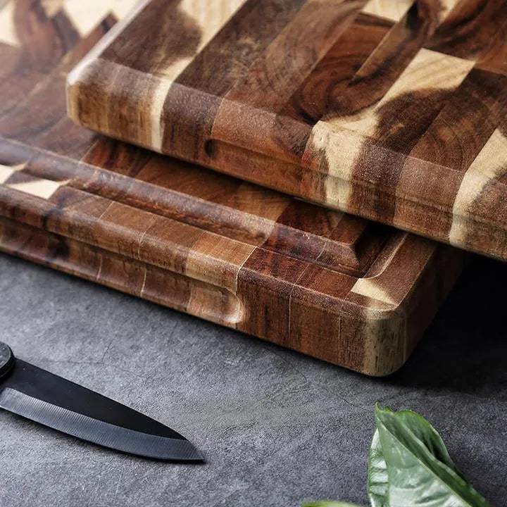 Brown solid acacia wood chopping board with 3cm thickness on a kitchen counter.