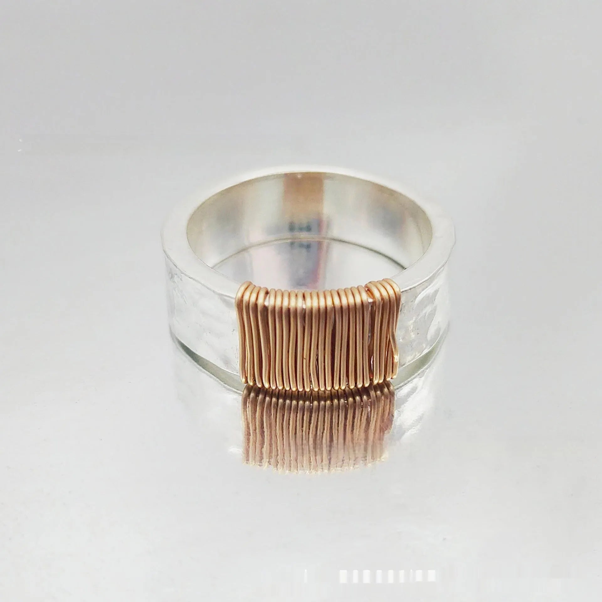 Geometric copper bracelet with irregular coil pattern forming silver-gold wide-faced ring design
