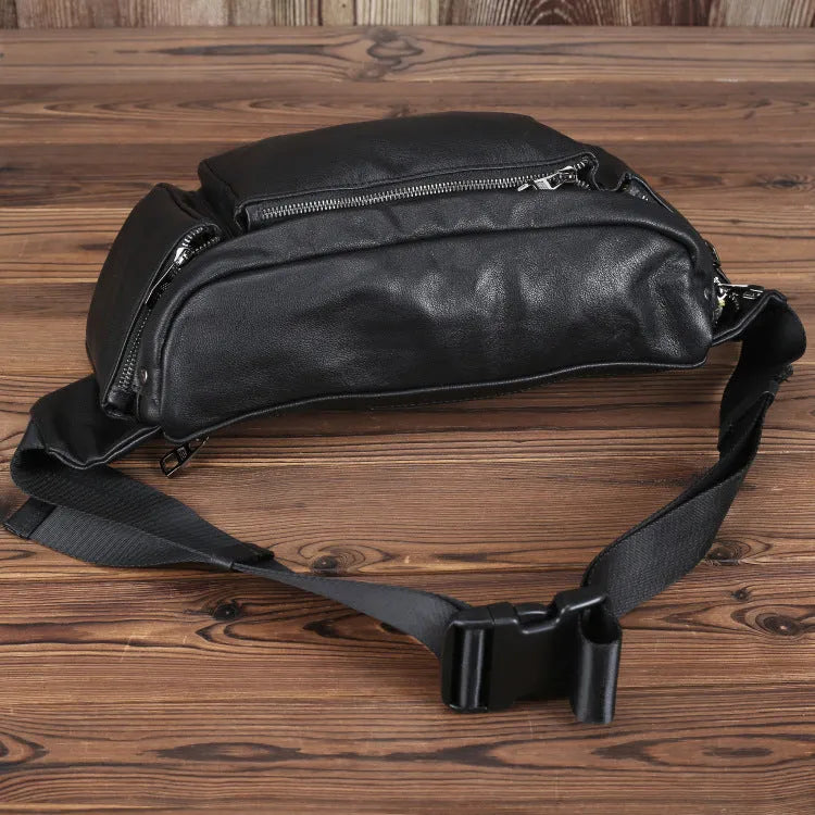 Black cowhide leather messenger bag with large capacity, oval shape, and zipper closure – worn over the shoulder as a crossbody bag