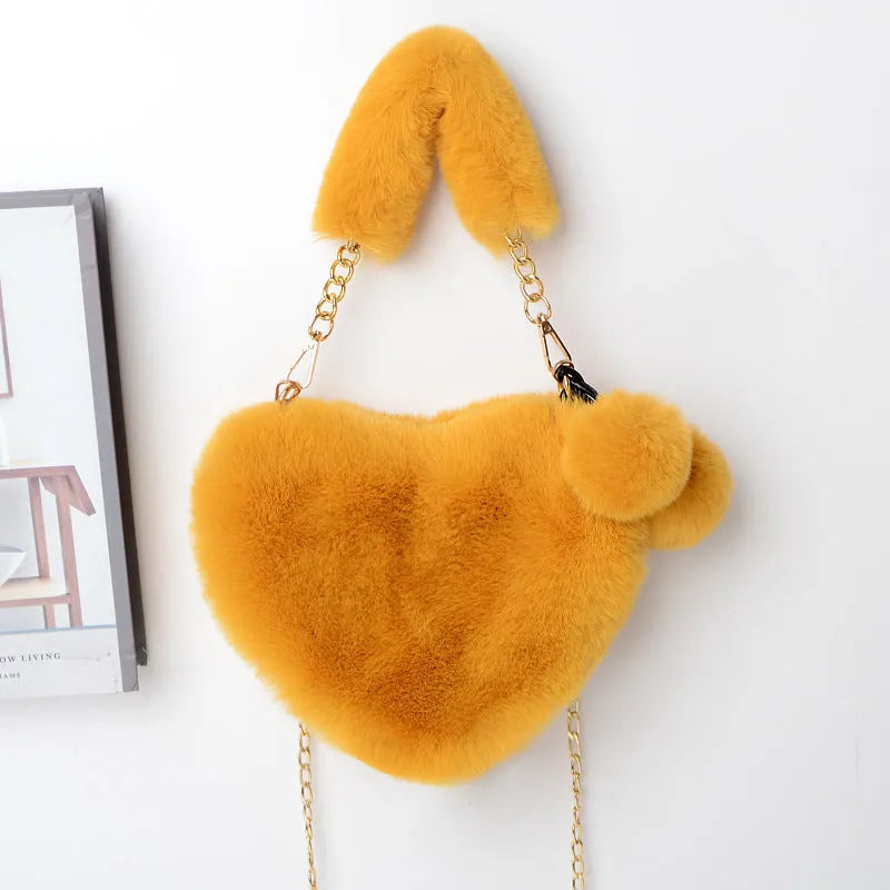 A soft, heart-shaped plush handbag for women in a medium size with a detachable shoulder strap.